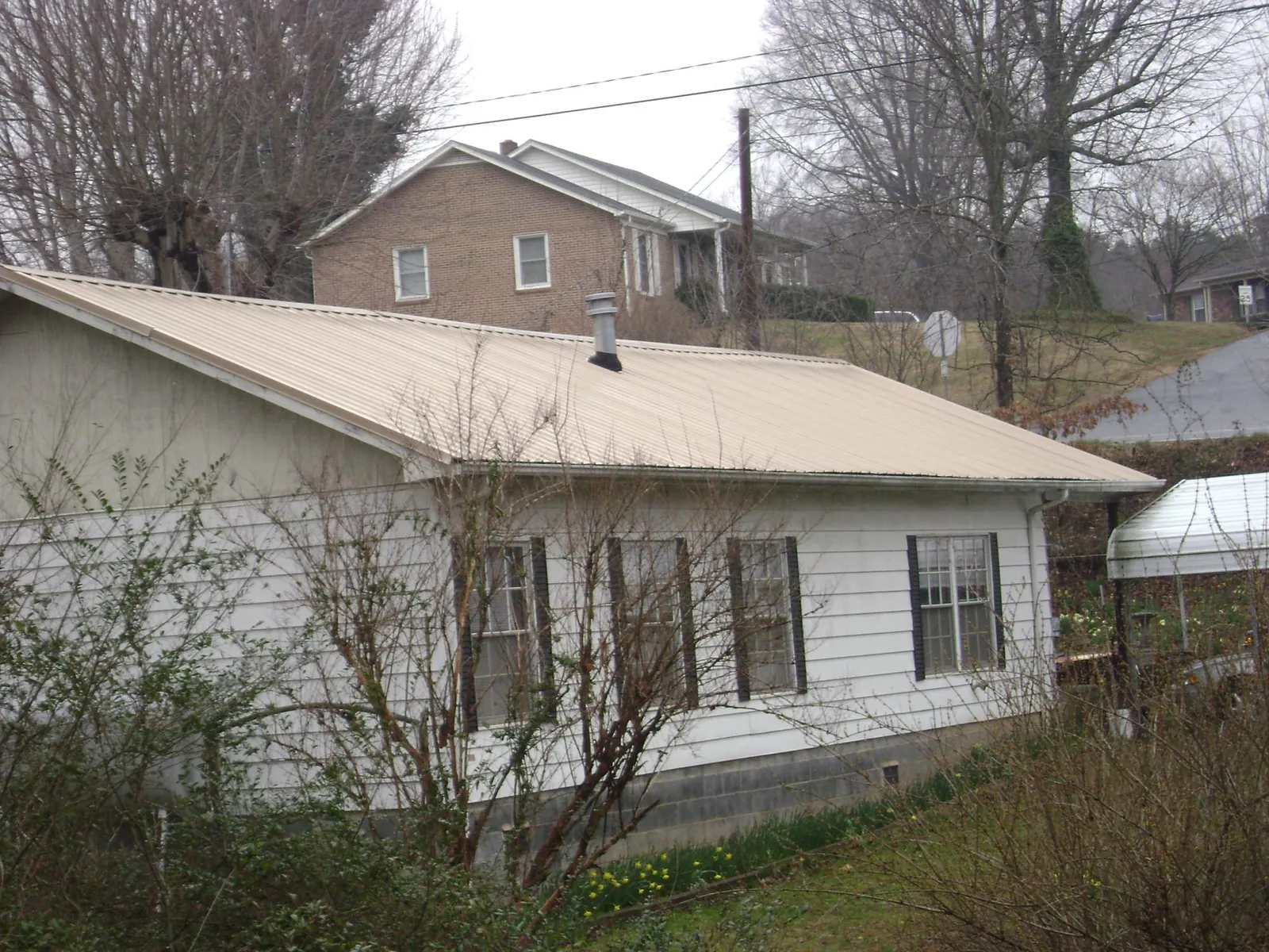 Tan metal roof on a white sided house set into a hillside — Commercial Roofing by Roofing Brothers in Marina Del Rey